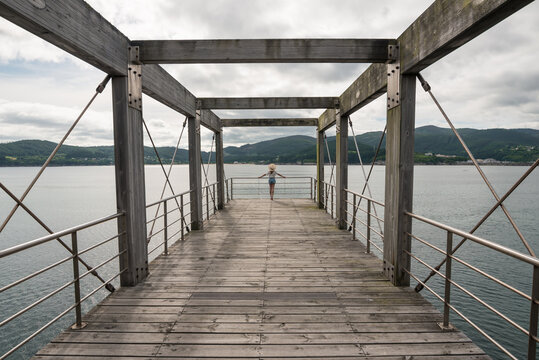 Female traveler on wooden pier near sea