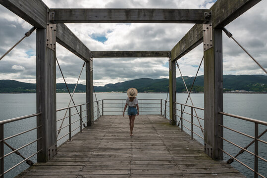 Female traveler on wooden pier near sea