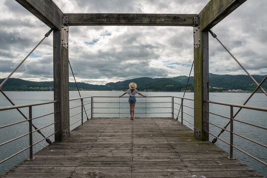 Female traveler on wooden pier near sea