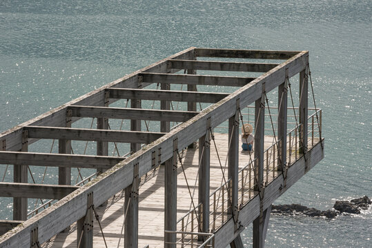 Woman sitting on pier against calm sea
