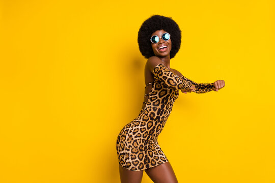 Photo of funky shiny dark skin lady wear off-shoulders clothes eyewear dancing empty space smiling isolated yellow color background