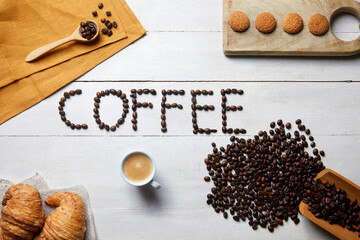 The word coffee written with coffee beans on a white wooden table