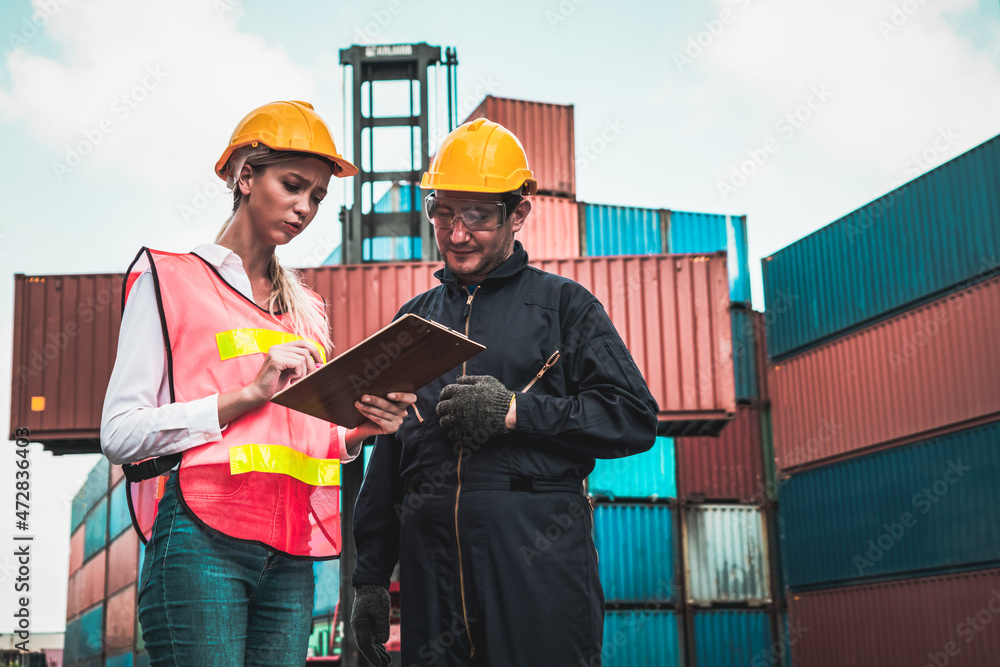 Wall mural Industrial worker works with co-worker at overseas shipping container yard . Logistics supply chain management and international goods export concept .