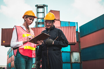 Industrial worker works with co-worker at overseas shipping container yard . Logistics supply chain...