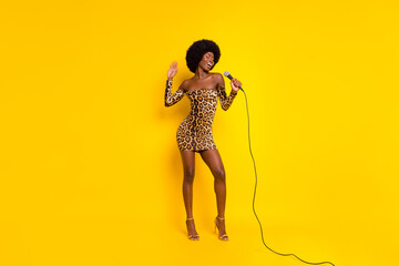 Photo of funny charming dark skin woman dressed leopard outfit smiling singing isolated yellow color background © deagreez