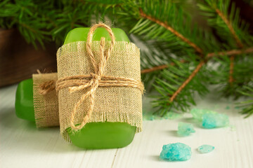 green soap made of environmentally friendly materials on a wooden background. Fir branches in the background