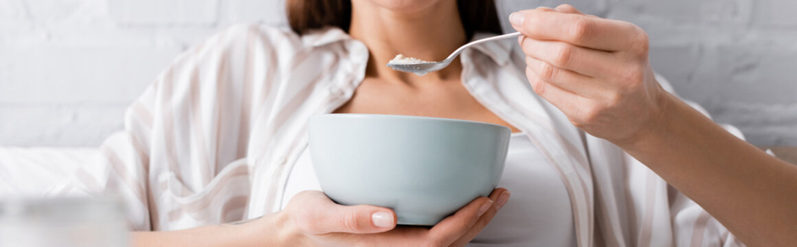 cropped view of young woman eating oatmeal, banner.