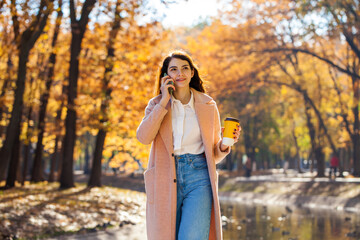 Young business woman making a cell phone call in autumn park