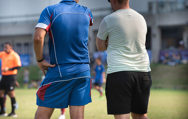 Head football coach discusses with his staff coach during a match in a high school soccer tournament.