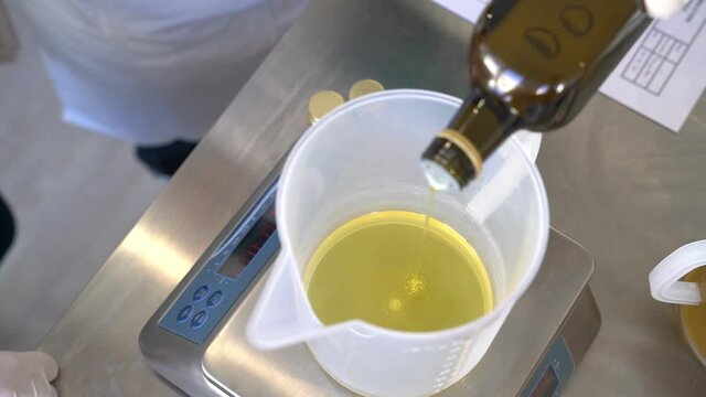 Pouring palm oil on a measuring cup and using weight scale for the preparation of hand soap mixture, Close up top shot