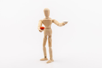 A wooden Gestalta doll or mannequin holds red and white pills in its hands on light background. The concept of choice.