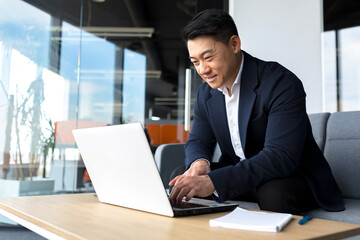 Successful and happy asian man working online remotely on laptop smiling happy with plan and task