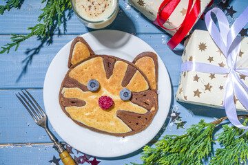 Christmas New Year morning breakfast, kids festive brunch snack. Funny  tiger pancakes, creative New Year 2022 symbols pancakes made with with berries, chocolate and vanilla dough