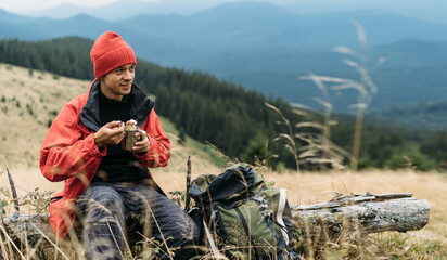 Tourist food in the mountains. Male traveler eating instant noodles looking at the mountain,...