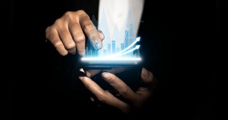 Person holding a mobile phone and pointing finger at the screen, graphic charts and fluctuations in financial data, showing business growth. Business strategy. digital business hologram.