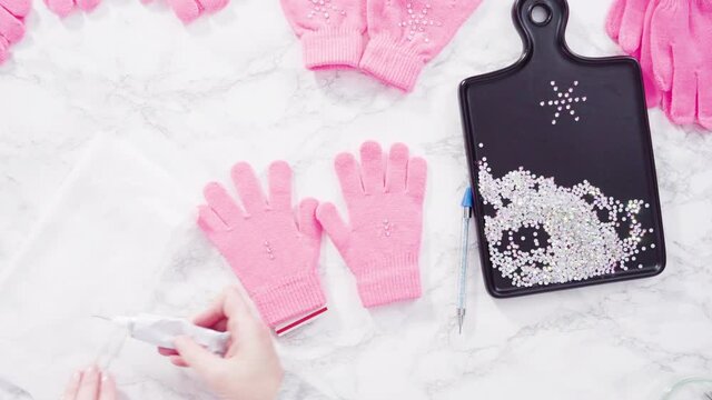 Flat lay. Rhinestone pink kids gloves with snowflake shapes.
