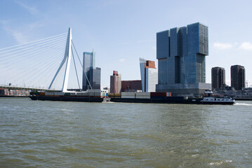 Obraz premium Erasmusbrug in the center of Rotterdam over the river Nieuwe Maas with a large cargo ship in the Netherlands