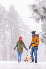 Couple walking and pulling sled on snowy winter day