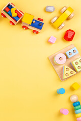 Baby kids toy for children. Educational wooden and plastic toys on yellow background. Top view, flat lay - obrazy, fototapety, plakaty