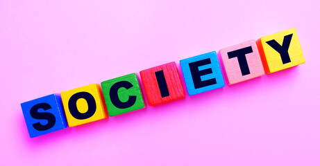 On a light pink background, multi-colored wooden cubes with the text SOCIETY