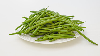 Fresh raw organic green beans in a bowl close up on white background