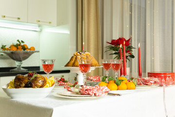Beautifully decorated festive table with baked chicken, homemade cake, glasses of wine and candles. Baked chicken for Thanksgiving, Christmas and New Year.