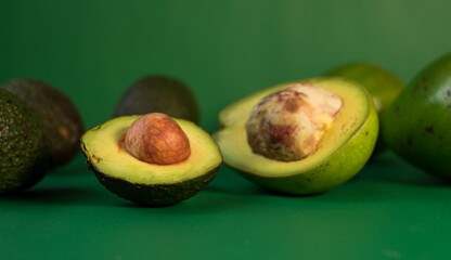 Some fresh avocados and hass avocado on a green background 