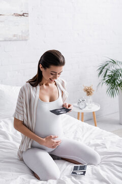 happy pregnant woman holding ultrasound scan.