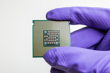 gloved hand holds a cpu, production of central processing units
