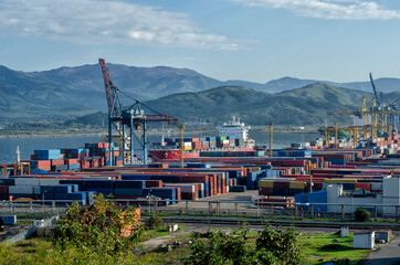 Sea cargo port container terminal framed by mountains.