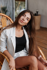 Obraz na płótnie Canvas beautiful brunette woman with long hair in a white jacket resting in a bungalow