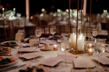 Wooden wedding table decorated with white candles white cloth Served table for dinner on the wedding party at the luxury hotel restaurant table set up for a special event with candles indoor 