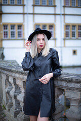 White european young girl with blonde hair in total black with building behind