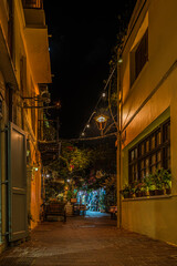 a illuminated narrow alley with gardens and restaurants in the old town of Chania