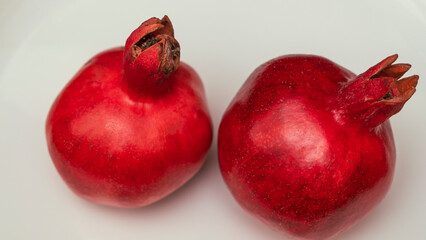 Two fruit juicy Spanish pomegranate on porcelain plate.