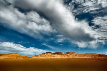Fototapeta na wymiar Cloudscape over eroded hills in the Atacama desert in the north of Chile