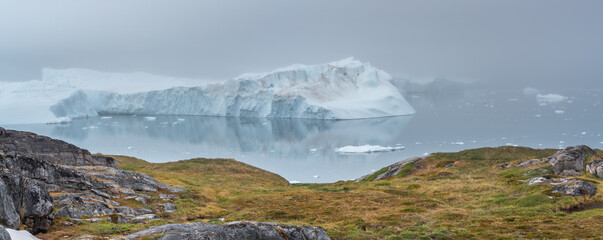 Panorama image of a landscape with icebergs floating in the mouth of the Ilulissat icefjord in west Greenland
