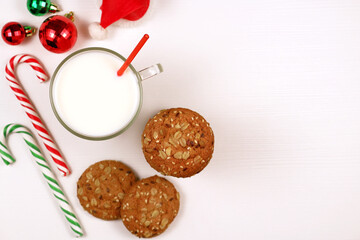 Christmas oatmeal cookies and glass of milk for Santa Claus on white background top view. Christmas greeting card with copy space.	