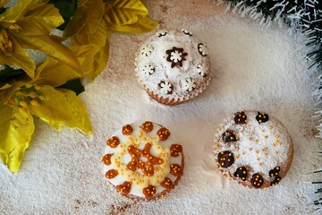 Christmas composition: Christmas cupcakes decorated with icing and surrounded by cinnamon sticks and star anise on a background of powdered sugar
