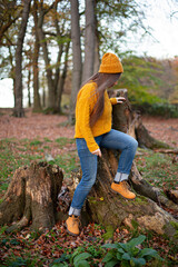 European white young woman in yellow sweater on autumn tree roots