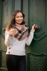 Smiling young european white woman with brown hair in a scarf near the old door