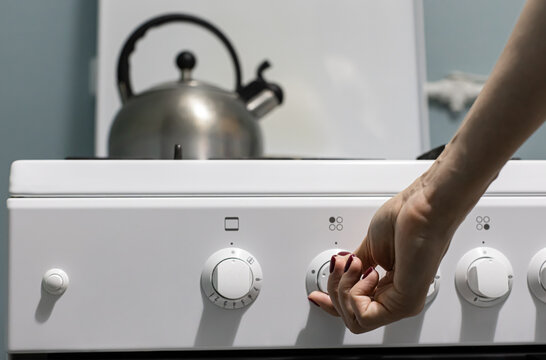 a person adds gas on the stove where the kettle is