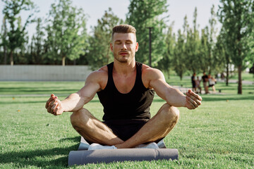 sporty man sitting on the lawn in the park training