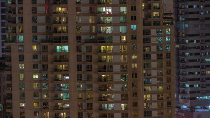 Fototapeta na wymiar Windows in high-rise building exterior in the late evening with interior lights on timelapse