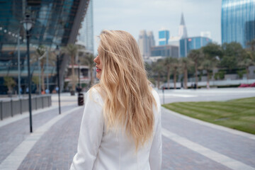 Fototapeta na wymiar Young beautiful blonde woman enjoying time over walking in Dubai downtown. Enjoying travel in United Arabian Emirates. Vacation and sightseeing concept