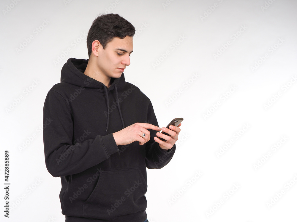 Poster man with smartphone in his hands. guy in a black hoodie touches the mobile phone screen with his fin