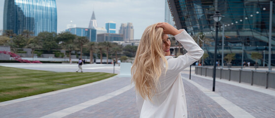 Young beautiful blonde woman enjoying time over walking in Dubai downtown. Enjoying travel in...