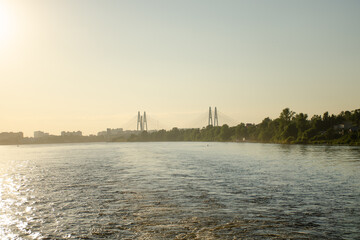 A river with a green forest along the banks and a road bridge in the distance