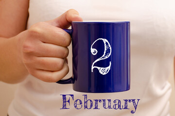 The inscription on the blue cup 2 february. Cup in female hand, business concept