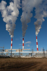 industrial chimneys with heavy smoke causing air pollution on the blue sky background